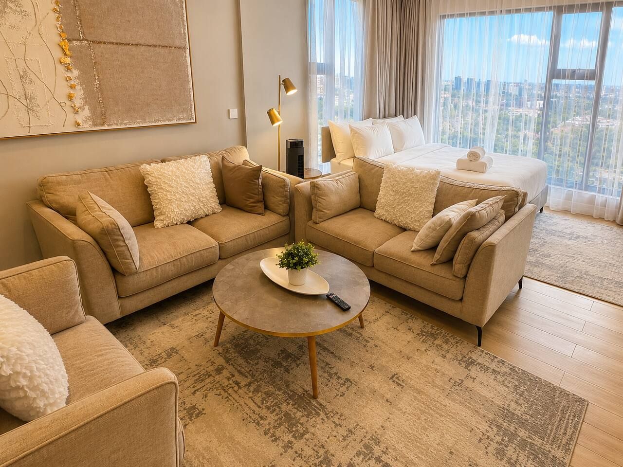 Une chambre d’hôtel moderne avec un grand lit, deux canapés, une table basse et une vue sur la ville.