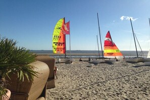 Een strand met windsurfspullen en een rieten stoel.