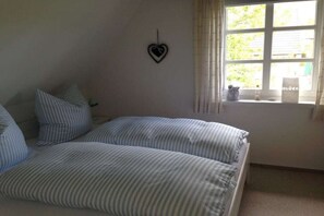 Ein Schlafzimmer mit zwei Betten, einer herzförmigen Dekoration an der Wand und einem Fenster mit Vorhängen.