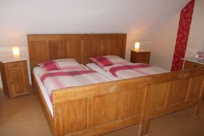 A double bed with a wooden headboard, two bedside tables, and a red patterned curtain. - Holiday apartment with 3 bedrooms (Ebersburg)