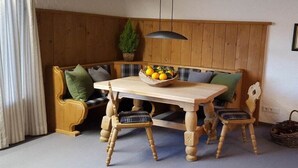 Um banco de madeira com mesa e cadeiras, um lustre pendurado e um vaso de planta.