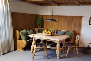 A wooden bench with a table and chairs, a hanging light fixture, and a potted plant. - Holiday apartment with 2 bedrooms (Sonthofen)