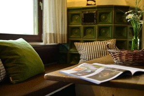 A room with a wooden bench, a magazine, a green vase with flowers, and a patterned wall. - Holiday apartment with 2 bedrooms (Sonthofen)