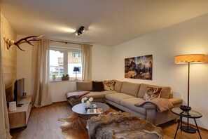 A modern living room with a sofa, coffee table, and a television. - Cabin in Inzell with swimming pool (Inzell)