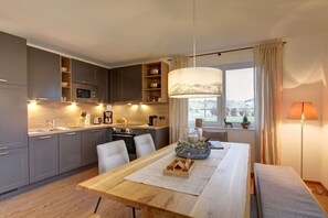 A modern kitchen with grey cabinets, a wooden dining table, and a view of the outdoors.