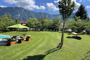 A well-maintained lawn with a pool, lounge chairs, and a sculpture.