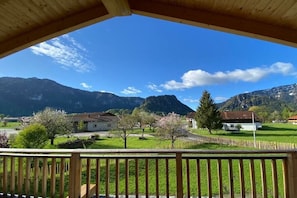 Ein Holzbalkon mit Blick auf eine ländliche Landschaft mit Häusern, Bäumen und Bergen.