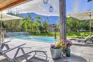 A poolside area with lounge chairs, umbrellas, and a view of mountains. - Cabin in Inzell with swimming pool (Inzell)