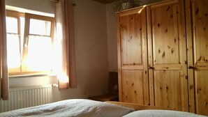 Quarto com duas camas, guarda-roupa de madeira e janela com cortinas.