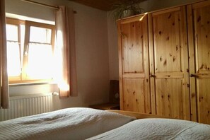 Une chambre avec deux lits, une armoire en bois et une fenêtre avec des rideaux.