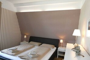A hotel room with a bed, two bedside tables, and a lamp on a desk. - Holiday apartment with 4 bedrooms (Wangerooge)