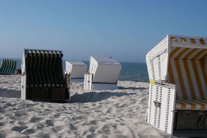 Sedie da spiaggia disposte su una spiaggia sabbiosa, con l'oceano sullo sfondo.