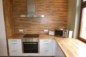 A modern kitchen with a wooden backsplash, stainless steel appliances, and a window providing natural light. - Holiday apartment with 4 bedrooms (Wangerooge)