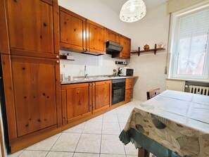 A kitchen with wooden cabinets, a microwave, and a sink. - Galileo Ferraris Apartment, Short-Term Rentals in the City of Vercelli (Vercelli)