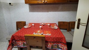 A kitchen with wooden cabinets, a tiled backsplash, and a table set with plates and cups. - Galileo Ferraris Apartment, Short-Term Rentals in the City of Vercelli (Vercelli)