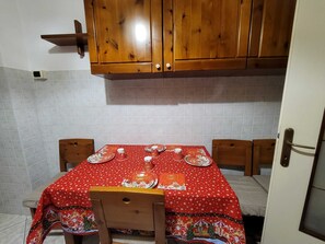 Una cucina con mobili in legno, zoccolo di piastrelle e tavolo apparecchiato con piatti e tazze.