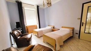 A hotel room with a bed, a chair, a desk, and a window with curtains. - Galileo Ferraris Apartment, Short-Term Rentals in the City of Vercelli (Vercelli)