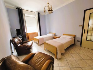 Una camera d'albergo con un letto, una sedia, una scrivania e una finestra con tende.
