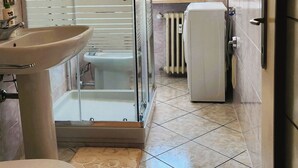 A bathroom with a glass-enclosed shower, a sink, a toilet, and a radiator. - Galileo Ferraris Apartment, Short-Term Rentals in the City of Vercelli (Vercelli)