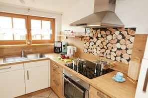 A modern kitchen with a wooden countertop, stainless steel appliances, and a window with a view. - Wiesenblick - Family Herb (Rettenberg)