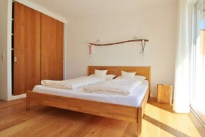 A room with a wooden bed, a wardrobe, and a window. - Holiday apartment with 2 bedrooms (Chieming)