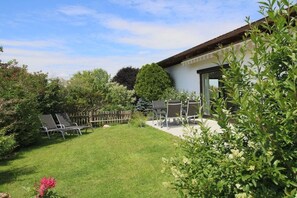 A backyard with a patio, a wooden fence, and various plants. - Holiday apartment with 2 bedrooms (Chieming)