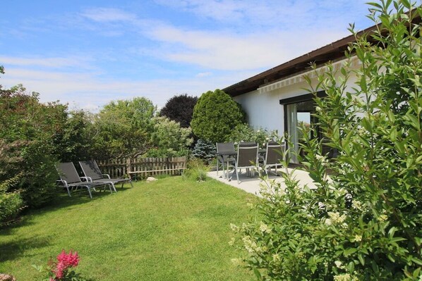 A backyard with a patio, a wooden fence, and various plants. - Holiday apartment with 2 bedrooms (Chieming)