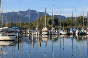 A marina with multiple boats docked, calm water, and mountains in the background. - Holiday apartment with 2 bedrooms (Chieming)