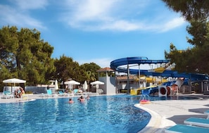 Une piscine avec des toboggans et des chaises longues.