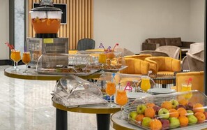 Montaje de un bufé de desayuno con una exhibición de frutas, dispensadores de jugo y una máquina de café.