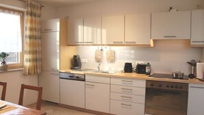 Una cucina con mobili bianchi, lavastoviglie, piano cottura e lavello.