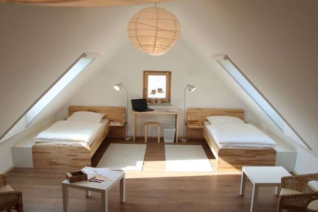 Ein kleines, gemütliches Schlafzimmer im Dachgeschoss mit zwei Einzelbetten, einem Schreibtisch und einem Stuhl.