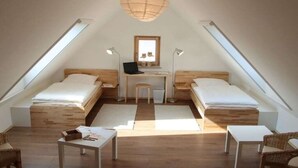 Una camera da letto mansardata accogliente con due letti singoli, una scrivania e una sedia.
