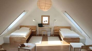 Ein kleines, gemütliches Schlafzimmer im Dachgeschoss mit zwei Einzelbetten, einem Schreibtisch und einem Stuhl.