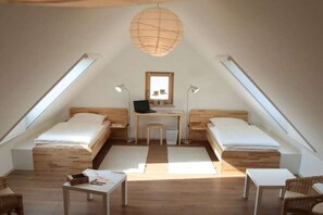 Ein kleines, gemütliches Schlafzimmer im Dachgeschoss mit zwei Einzelbetten, einem Schreibtisch und einem Stuhl.