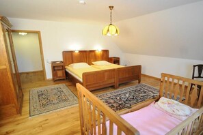 A bedroom with a wooden bed, bedside tables, a nightstand, a hanging light fixture, and a patterned rug. - Holiday apartment with 2 bedrooms (Wunstorf - Idensen)