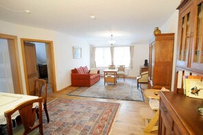 A spacious living area with a sofa, dining table, chairs, and a cabinet. - Holiday apartment with 2 bedrooms (Wunstorf - Idensen)