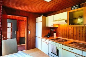Een kleine keuken met houten wanden, een inbouwoven en een fornuis.