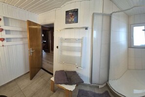 Ein Badezimmer mit Holztür, Handtuchhalter und einer Bank.