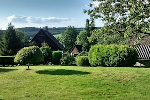 A rural landscape with a large barn and a smaller building, surrounded by well-maintained grass and trees. - Vedder's Mountain Hut (Herscheid)