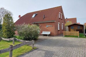 Un bâtiment en briques avec un toit en pente, un banc et une clôture en bois.