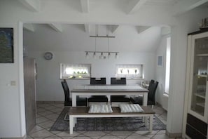 A dining area with a table, chairs, a bench, a rug, and a ceiling light fixture. - Holiday home with 2 bedrooms (Nessmersiel)