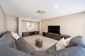 A modern living room with a sofa, a coffee table, a flat-screen TV, and a fireplace. - CONTEMPORARY LUXE THREE-STOREY HOLIDAY HOME IN A TRANQUIL BEACHSIDE LOCATION (Dunsborough)