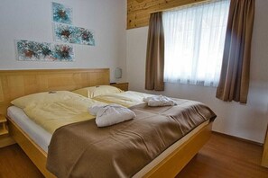 A double bed with a wooden headboard, a bedside table, and a window with curtains. - Apartment in Forstau with sauna and balcony (Forstau)
