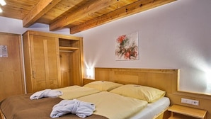 A double bed with a wooden headboard, a wooden wardrobe, and a painting on the wall. - Apartment in Forstau with sauna and balcony (Forstau)