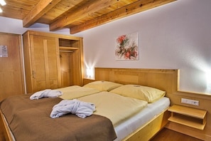 Un lit double avec une tête de lit en bois, une armoire en bois et un tableau accroché au mur.