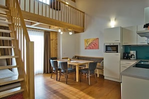 Une cuisine moderne avec un coin repas, un escalier en bois et un tableau au mur.