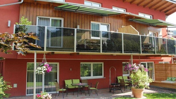 A two-story building with a balcony, outdoor seating, and hanging flower baskets. - Apartment in Forstau with sauna and balcony (Forstau)