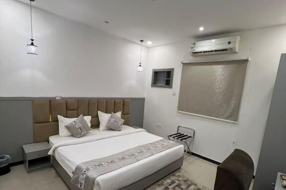 A modern bedroom with a bed, bedside tables, a rug, and an air conditioning unit.