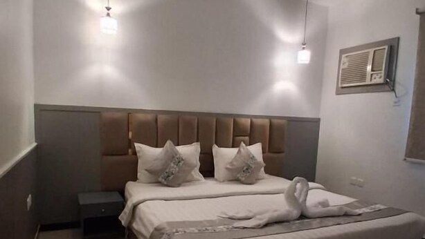 Een hotelkamer met een groot bed, een nachtkastje en een wandgemonteerde airconditioning.